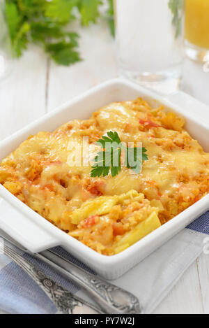 Stillleben mit cheesy Gemüseauflauf auf weissem Holztisch Stockfoto