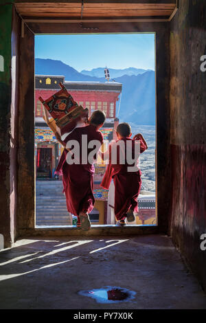 Zwei junge Mönche gehen durch eine Tür an der Thiksey Kloster, Ladakh, Jammu und Kaschmir, Indien Stockfoto