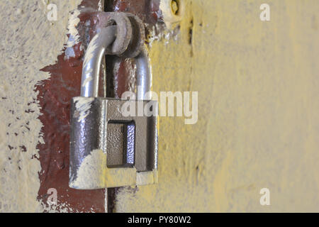 Nahaufnahme der rostigen alten key lock auf der lackierten weiße Wand. Dirty Vorhängeschloss auf der lackierten Metall Tür Stockfoto