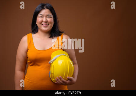 Gerne asiatische Frau Bauarbeiter Holding hardhat Stockfoto