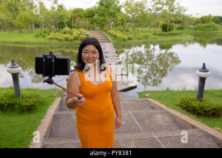 Asiatische Frau unter selfie mit Handy befestigen Stick im Park zu selfie Stockfoto