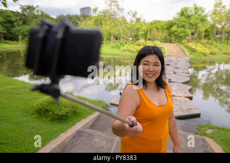 Asiatische Frau unter selfie mit Handy befestigen Stick im Park zu selfie Stockfoto
