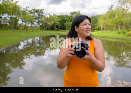 Schöne Übergewicht asiatische Frau Fotograf im Park lächelnd Stockfoto