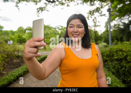 Schöne Übergewicht asiatische Frau unter selfie in Park Stockfoto