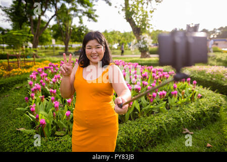 Asiatische Frau unter selfie mit Handy befestigen Stick im Park zu selfie Stockfoto