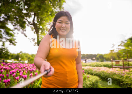 Asiatische Frau unter selfie mit Handy befestigen Stick im Park zu selfie Stockfoto