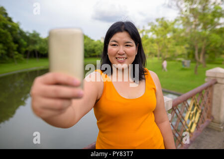 Schöne Übergewicht asiatische Frau unter selfie in Park Stockfoto