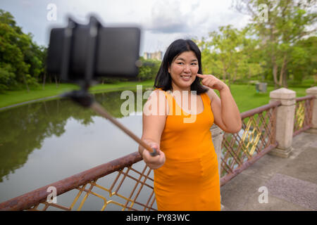 Asiatische Frau unter selfie mit Handy befestigen Stick im Park zu selfie Stockfoto