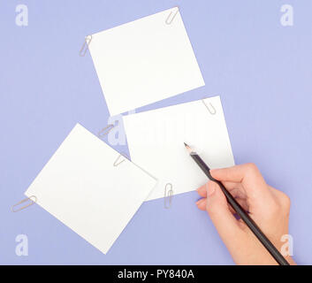 Frauen Hand schreiben auf Hinweis Papiere auf lila Hintergrund. Blanks Blatt Papier und Buntstifte auf Violett Hintergrund. Kopieren Sie Platz Stockfoto
