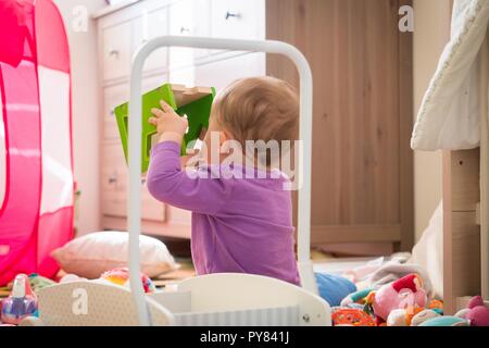 Wenig Kleinkind spielen mit einem hölzernen Shape Sorter Cube in seinem Zimmer Stockfoto