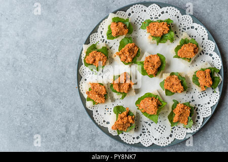 Canape mit Muhammara, Adjika, Ajika oder Acuka auf kleine quadratische Brote mit runder Platte. Traditionelle organische Vorspeise. Stockfoto