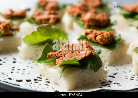 Canape mit Muhammara, Adjika, Ajika oder Acuka auf kleine quadratische Brote mit runder Platte. Traditionelle organische Vorspeise. Stockfoto