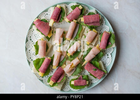 Canape Schinken umwickelt mit Käse und Grüns in der runde Platte. Organische Vorspeise. Stockfoto