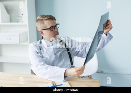 Junge kaukasier Arzt sitzt in seinem Büro und suchen X-ray Image Stockfoto