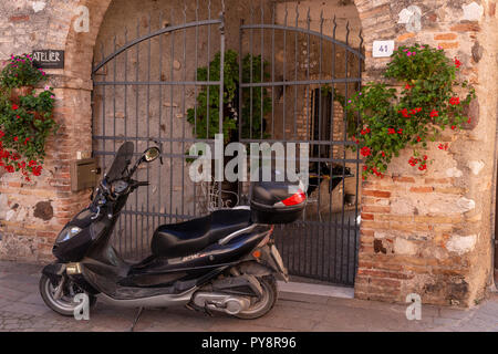 Scooter durch ein Tor von Castellaro Laguselo in Norditalien Stockfoto