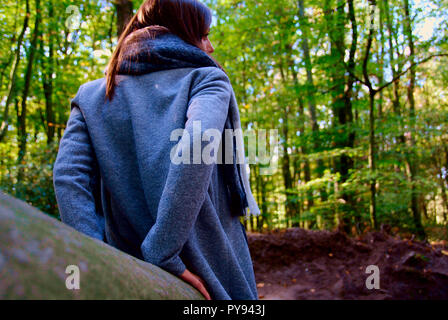 Eine schöne Frau auf einem Baumstamm im Wald in Duisburg sitzen in Deutschland Stockfoto