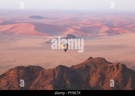 Namibia Travel - Heißluftballon bei Sonnenaufgang über den Sanddünen der Namib-Wüste - Beispiel für Adventure Travel, Namibia Afrika Stockfoto