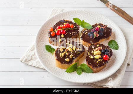 Sandwiches mit Schokoladencreme, Pistazien und frische Beeren auf einer Platte Stockfoto