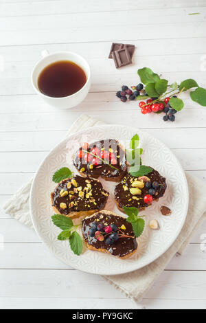 Sandwiches mit Schokoladencreme, Pistazien und frische Beeren auf einer Platte Stockfoto