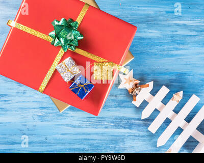 Big Red Christmas gift Box mit kleineren Boxen auf Blue vintage Holz- Hintergrund. Feier Symbol. Stockfoto