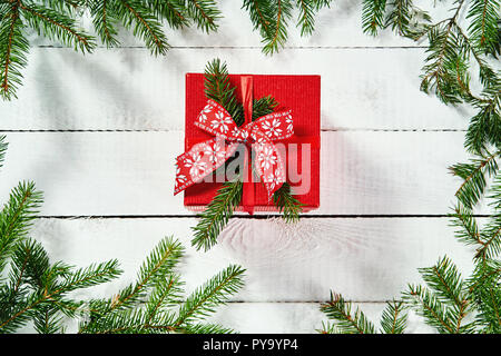 Ansicht von oben ein rotes Weihnachtsgeschenk auf einem alten weißen Holztisch mit Zweige Fichte Stockfoto