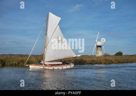 Eine gebrochene Sloop Segelboot, eine Windmühle auf dem Fluss Thurne, die auf einem klaren Herbstmorgen, Norfolk Broads, Norfolk, England, Großbritannien Stockfoto