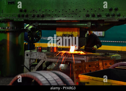 Detail - Teil einer Maschine. Heiße Eisen in den weiterverarbeitenden Betrieben, die ein Arbeitnehmer statt. Schwere Schmiedestücke Anlage. Metallverarbeitung Stockfoto