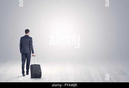 Junge Unternehmer in einem weißen grenzenlosen Raum gehen Mit zurück und Gepäck auf seiner Hand Stockfoto