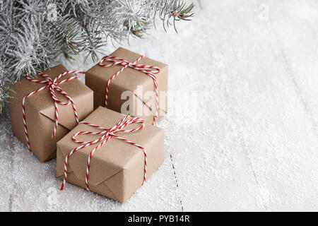 Weihnachten Geschenk Boxen in Kraftpapier unter schneebedeckten Tannenbaum Äste gewickelt, kopieren Raum Stockfoto