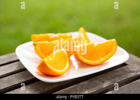 Orange Keile auf weiße Platte auf Holz Oberfläche mit grünem Hintergrund Stockfoto