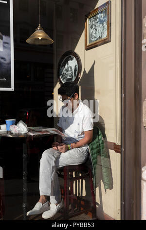 Ein Mann sitzt im sonnendurchfluteten Fenster in einem Londoner Café, am 25. Oktober 2018, in Piccadilly, London, England. Stockfoto