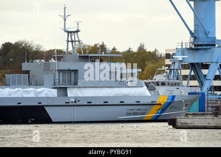 Wolgast, Deutschland. 25 Okt, 2018. 25. Oktober 2018, Deutschland, Wolgast: ein marineschiff (ein Schiff unbekannter Art) und ein Boot (Hintergrund) für Saudi-arabien liegen an der Ausrüstung Kai an der Peene Werft. Die bremer Luerssen-Gruppe, zu der der Wolgaster Werft gehört, die milliardenschweren Auftrag für den Bau einer Flotte von neuen Saudi Patrouillenboote erhalten hatte und begann den Bau im Jahr 2015. Quelle: Stefan Sauer/dpa-Zentralbild/ZB/dpa/Alamy leben Nachrichten Stockfoto