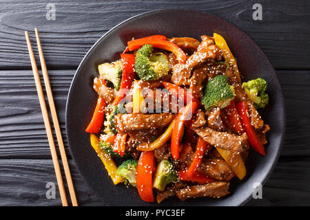 Wokgemüse teriyaki Rindfleisch mit roten und gelben Paprika, Brokkoli und Sesamsamen close-up auf einem Teller auf den Tisch. Horizontal oben Ansicht von oben Stockfoto