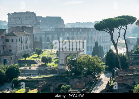 Am frühen Morgen Blick über das Forum Romanum zum Bogen des Titus, mit dem Kolosseum im Hintergrund, Rom, Italien. Stockfoto