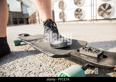 In der Nähe der Beine und Longboard stehen auf Asphalt. Stockfoto
