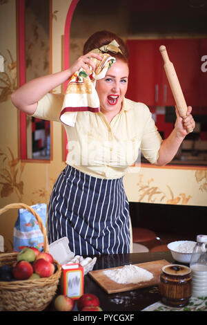 Emotional ausdrucksstarken Frau cute woman in der Küche. In den Händen halten Werkzeuge für das Kochen. Stockfoto