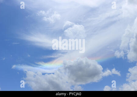 Ein himmlisches Meisterwerk, in dem ein lebhafter Regenbogen inmitten eines Meeres aus Baumwollwolken tanzt. Stockfoto