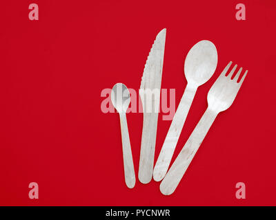 Hölzerne Löffel, Messer und Gabel auf weißem Hintergrund. Umweltfreundliche einweg Besteck auf Rot. Stockfoto