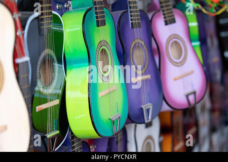 Reihen von bunten Praxis Gitarren für Kinder an der Wand hängen von einem Straßenhändler. Stockfoto