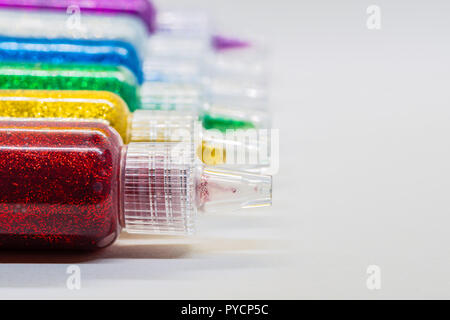 Reihen von bunten Glitter Glue Verlegung auf dem weißen Hintergrund. Stockfoto