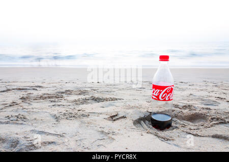 Kochi, Kerala, Indien - Januar 11, 2015: Fast leerer Kunststoff Coca Cola Flasche auf einen Fußabdruck im Sand am Arabischen Meer Strand in Kochi. Stockfoto