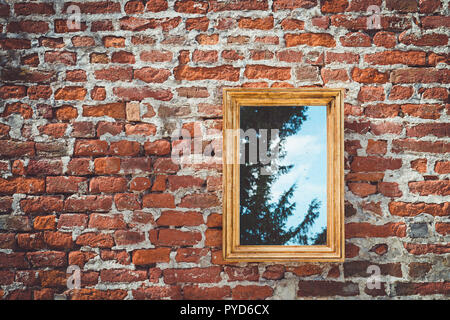 Alte Mauer mit goldenen Rahmen reflektierenden Spiegel Bäume mit Sky auf Hintergrund Stockfoto
