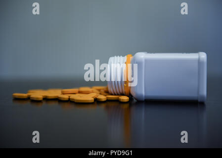 Gelbe Pillen zufällig auf den Schwarzen Tisch mit weißen Pille containr neben Ihnen Stockfoto