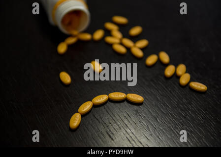 Traurige smiley mit gelben Pillen auf den Schwarzen Tisch Stockfoto