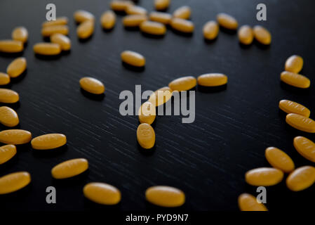 Traurige smiley mit gelben Pillen auf den Schwarzen Tisch Stockfoto
