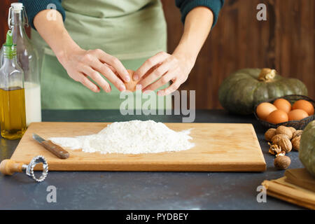 Hände kneten den Teig von Frauen. Der konditor ist ein Ei in das Mehl. Auf dem hölzernen Tisch backen Zutaten. Kürbis Mehl Öl Milch C Stockfoto