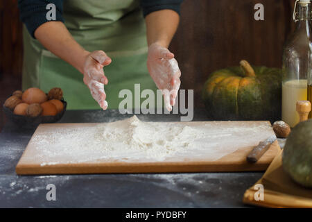 Hände kneten den Teig von Frauen. Backzutaten auf hölzernen Tisch Kürbis Milch Öl Mehl Kopie Raum Stockfoto