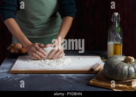 Hände kneten den Teig von Frauen. Backzutaten auf hölzernen Tisch Kürbis Milch Öl Mehl Kopie Raum Stockfoto