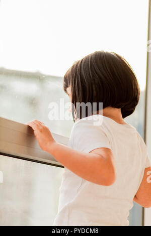 Ack Blick auf süße kleine Mädchen schaut aus dem Fenster Stockfoto