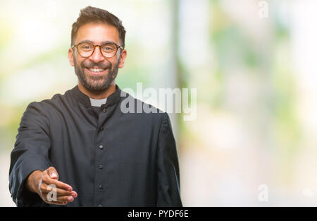 Nach spanischer katholischer Priester Mann über isolierte Hintergrund lächelt freundlich mit Handshake als Ansage und einladend. Erfolgreiches Business. Stockfoto